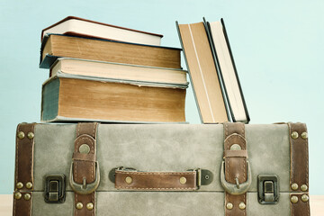 Old vintage suitcase and stack of books