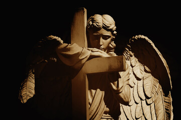 Death concept. Silhouette of angel with cross. Ancient statue.