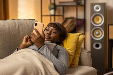 On the couch lies a happy girl who has managed to book a seat at the cinema online. The woman wants to tell the good news to her friend, about the reservation for next week.