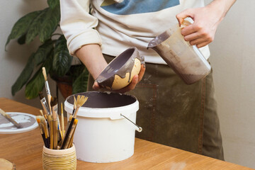 Potter Glazes Bowls in Workshop. Ceramic Artist Man glazing on master class. Pottery Making process, ceramic production