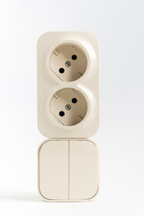 double socket and two-key light switch on white background. mechanical device for switching lighting circuit and two sockets connected by one monolithic case. shop of electronic devices for the home.