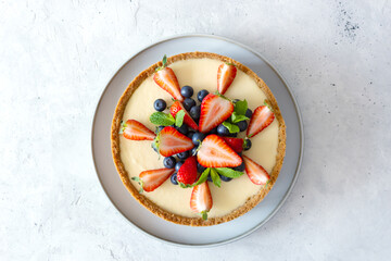 Traditional New York cheesecake on the gray plate. Served with strawberry, blueberry and mint. Top...