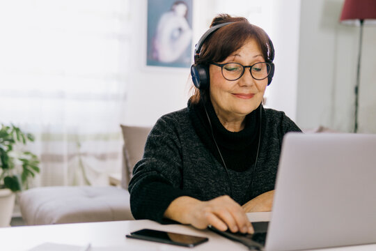 Middle aged woman works remotely from home - older mature people and technology concept.
