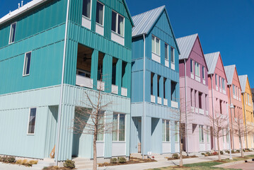 Corner of colorful new development three-story townhome style houses with metal roofs and enclosed balcony under sunny clear blue sky in Wheeler District, Oklahoma City, USA