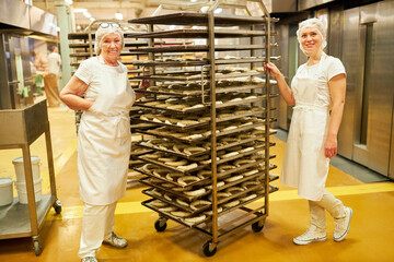 Two bakers women and a tray trolley with croissants