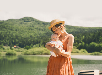 Fototapeta premium Mother and baby. Concept of natural maternity and motherhood. Beautiful woman and little baby happy together in green nature background. Loving mom with child outdoors.