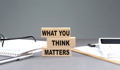 WHAT YOU THINK MATTERS text on wooden block with notebook,chart and calculator, grey background - obrazy, fototapety, plakaty