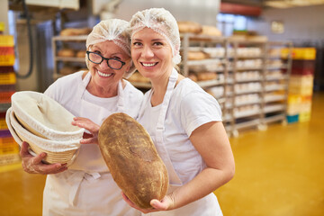 Baker apprentice and senior baker with a loaf of bread