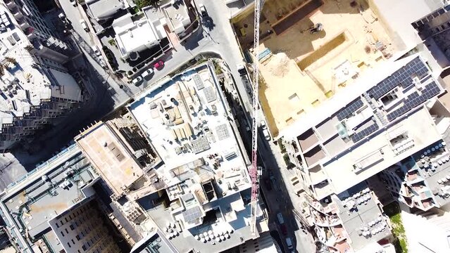 Industrial crane and building foundations near narrow streets of St. Paul Bay downtown in Malta. Top down aerial view