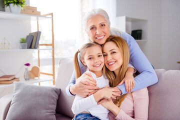 Fototapeta premium Portrait of three peaceful positive people cuddle sitting sofa toothy smile look camera house indoors