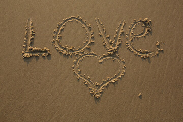 The tekst Love written in the sand and a heart drawn next to it

