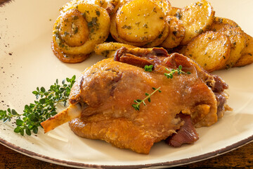 view of a duck leg confit with sarladaise potatoes on a plate
