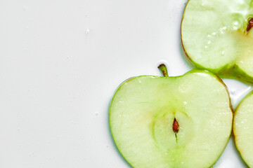 Top view of fresh sliced apples with juice or gel on white background, juice and gel serum, organic cosmetics, extract, flat lay, copy space.