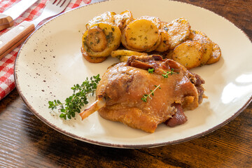 view of a duck leg confit with sarladaise potatoes on a plate