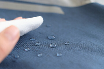 hand wipes drops of water from a cloth. Water drops on waterproof textile material. short depth of...