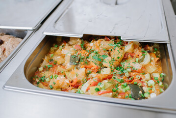 Different types of dishes in containers on the buffet table in the hotel restaurant