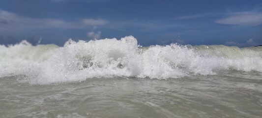 Beautiful beach on the ocean in the Dominican Republic. Close up image of blue water, macro. Great tropical paradise view. Sunny day. Clean sand, curly white waves. Photo can be used as wallpaper.