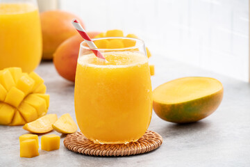 Fresh beautiful delicious mango juice smoothie in a glass cup on gray table background. - obrazy, fototapety, plakaty