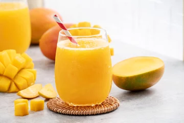 Poster Fresh beautiful delicious mango juice smoothie in a glass cup on gray table background. © RomixImage