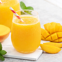 Fresh beautiful delicious mango juice smoothie in a glass cup on gray table background.