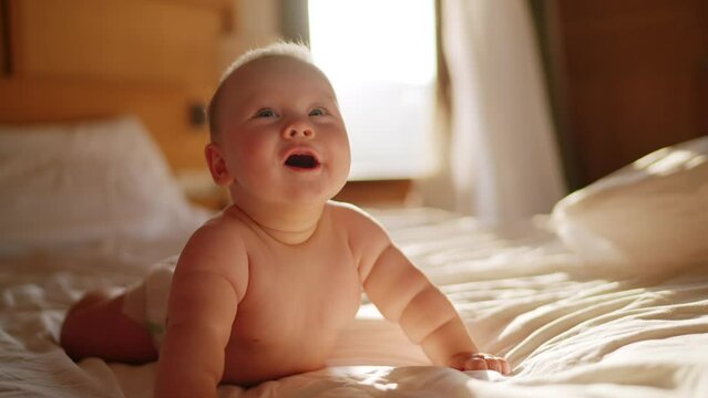 Beautiful Smiling Baby, gorgeous little baby lie on bed and smile at camera with nice soft focus background. Little girl or boy is humming, real original audio track, lovely asian baby playing at home