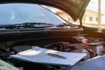 Fototapeta na wymiar Clipboard on car with car insurance claim form for customer maintenance vehicle checklist in auto repair shop garage.