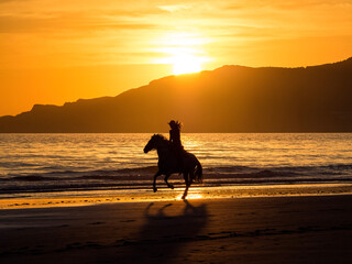 Tarifa, Spain woman on horseback on  the beach at sunset