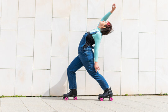Lady in roller skates dancing near building on street
