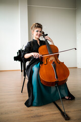 a beautiful girl plays the cello in the classroom, the cello plays and smiles at the camera © Ринат Куйшин