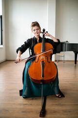a beautiful girl plays the cello in the classroom, the cello plays with a bow © Ринат Куйшин