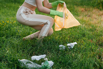 A girl in the park at sunset is engaged in garbage collection in the park. Environmental care,...