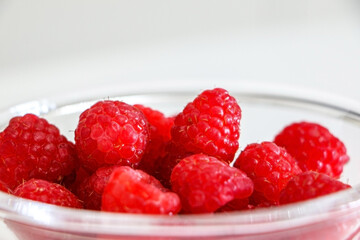 Close up or juicy and sweet raspberries in a glass bowl