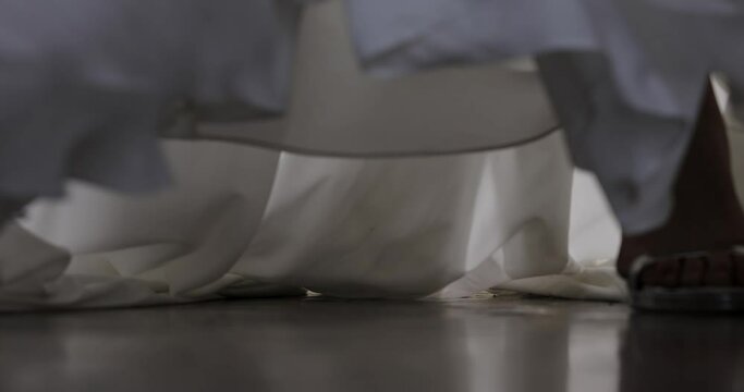 the steps of the bride in a white dress with beautiful shoes on the rebounds go to the camera against the backdrop of traffic of people. female steps in a wedding dress. close-up