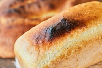 A piece of white homemade bread lies on the table in a wooden village house. Healthy and eco- friendly food.