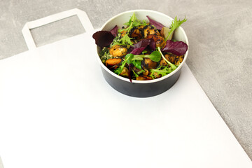 Salad with mussels, arugula and greens in a round takeaway paper container on gray background. Healthy food delivery concept. Banner. Top view. Free space for text.