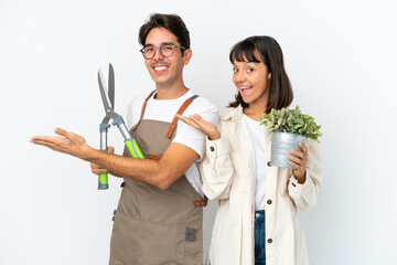 Young mixed race gardeners holding a plant and pruning shears isolated on white background...