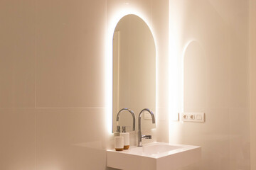 Minimal white luxury bathroom sink with arch-shaped mirror and integrated LED