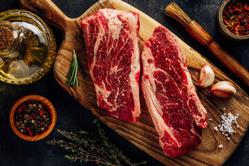 Top view raw meat marbled beef. Top blade steak on wooden cutting board with cook utensils and...