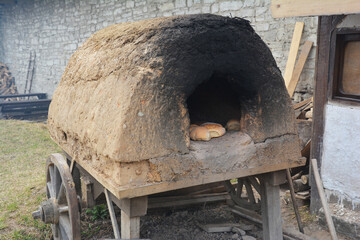 A reconstructed historic wooden cart, wooden wagon with a clay oven on top with baked bread. Baking...