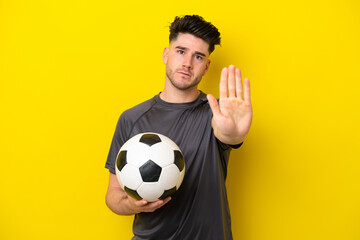 Handsome young football player man isolated on yellow background making stop gesture