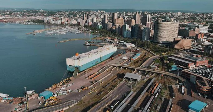 Aerial panning view of an Autoliner ship docked at Durban harbour, Durban city centre in background