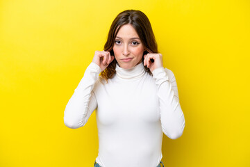 Young caucasian woman isolated on yellow background frustrated and covering ears