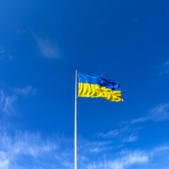 Flag of Ukraine on a flagpole filled with wind against a blue sky. Symbol or sign. Independence of the nation