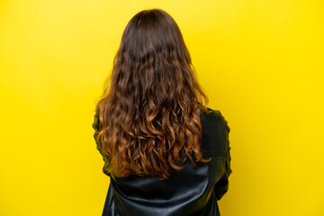 Fototapeta premium Young caucasian woman isolated on yellow background in back position
