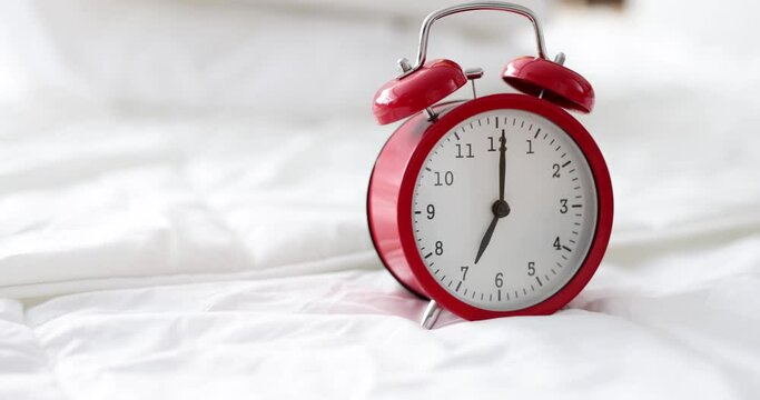 Alarm clock for seven o'clock on white bed