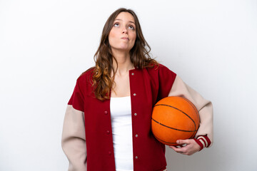 Young caucasian woman playing basketball isolated on white background and looking up