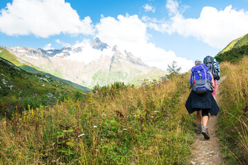 Young couple hiking in French Alps in summer. The Aiguille des Glaciers, mountain in the Mont Blanc massif. View From Chapieux valley, Savoie, France.