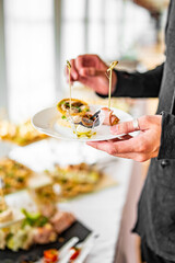 man hands take a snack and put it on plate. buffet in a restaurant