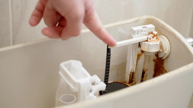 Finger pressing checks the performance of the float valve of the toilet bowl. Non-working mechanism for supplying water to the toilet flush tank