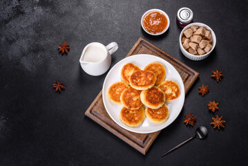 Fototapeta na wymiar Cottage cheese pancakes with oats, syrniki on a black rustic background